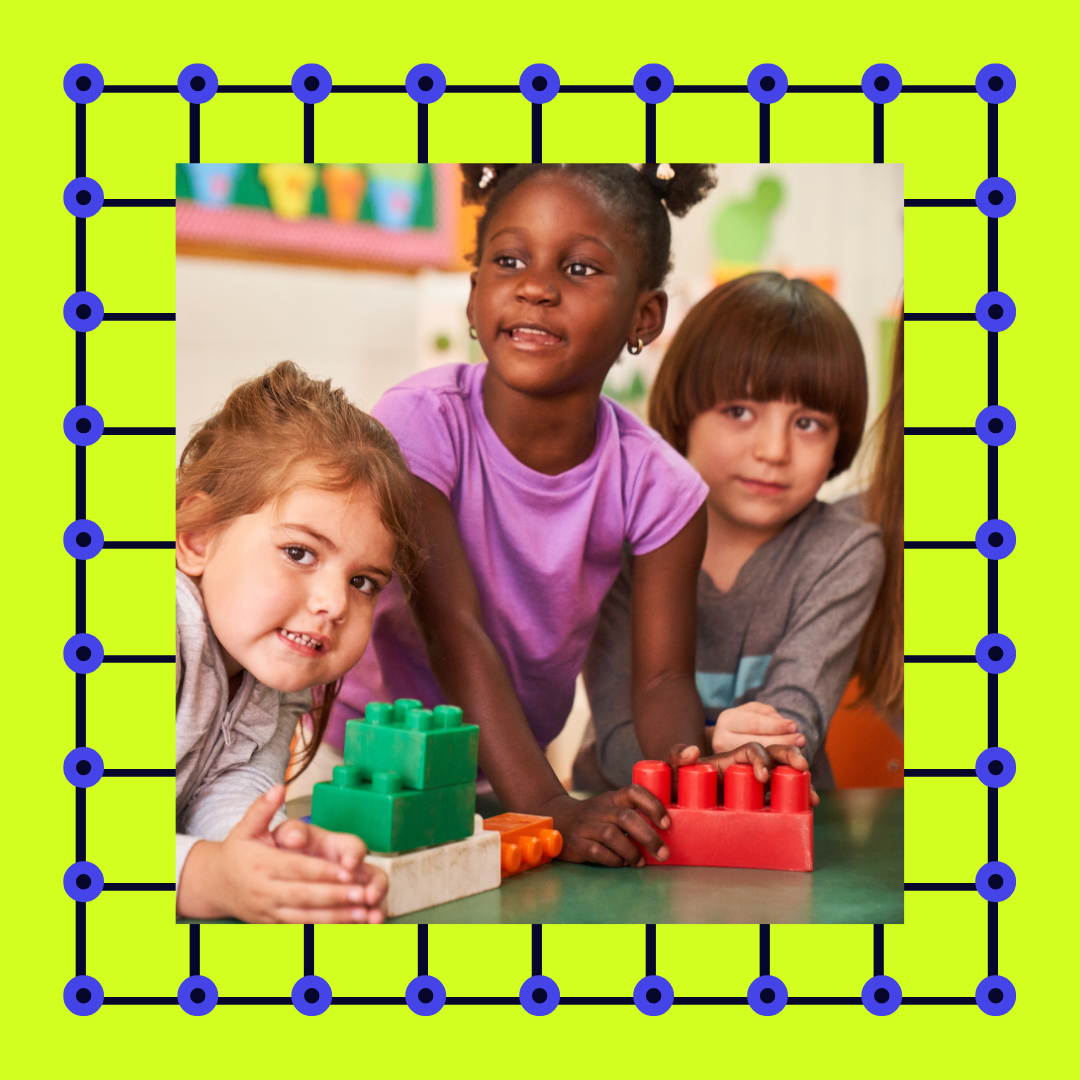 Three young girls playing with blocks at school