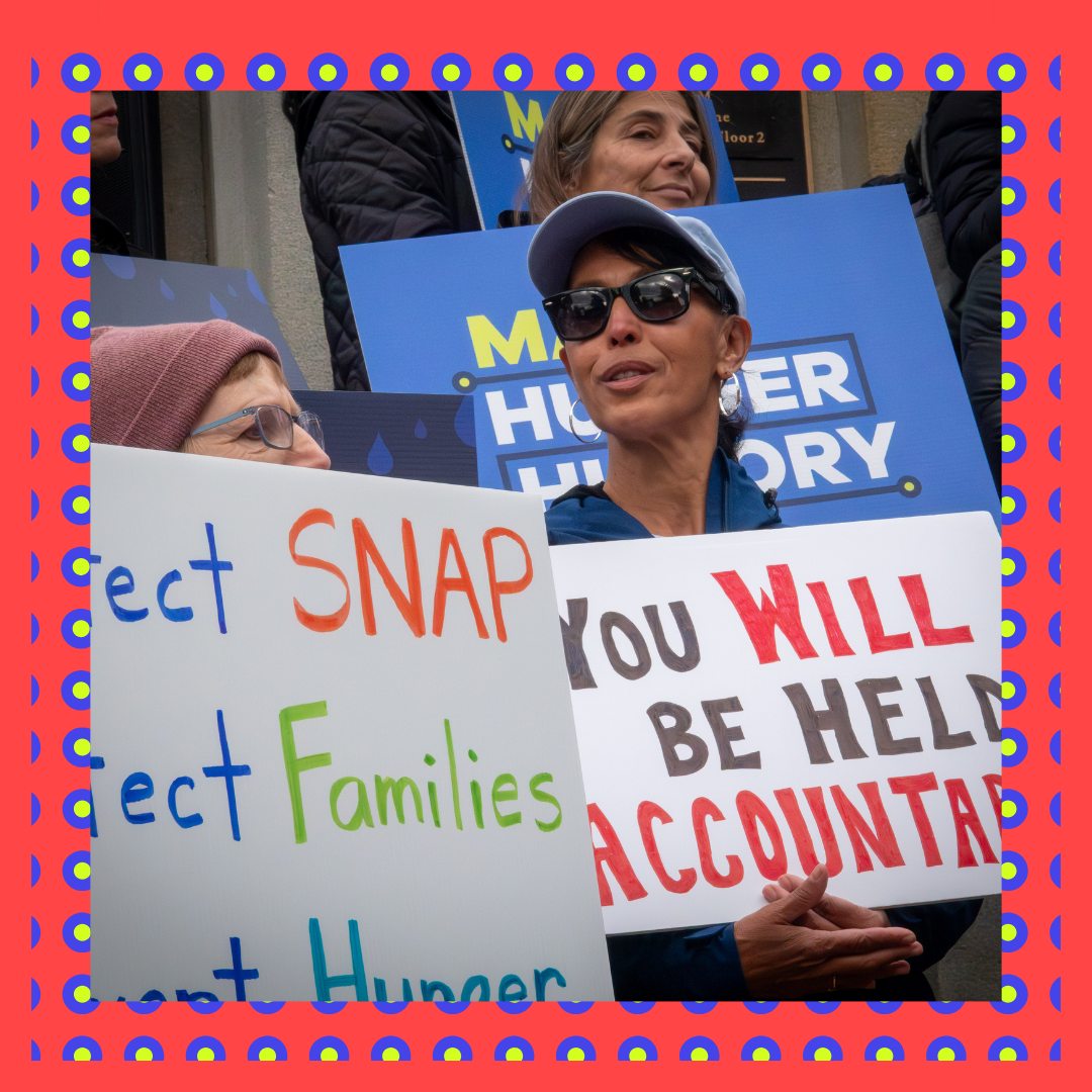People hold signs to protect SNAP at rally at the State House